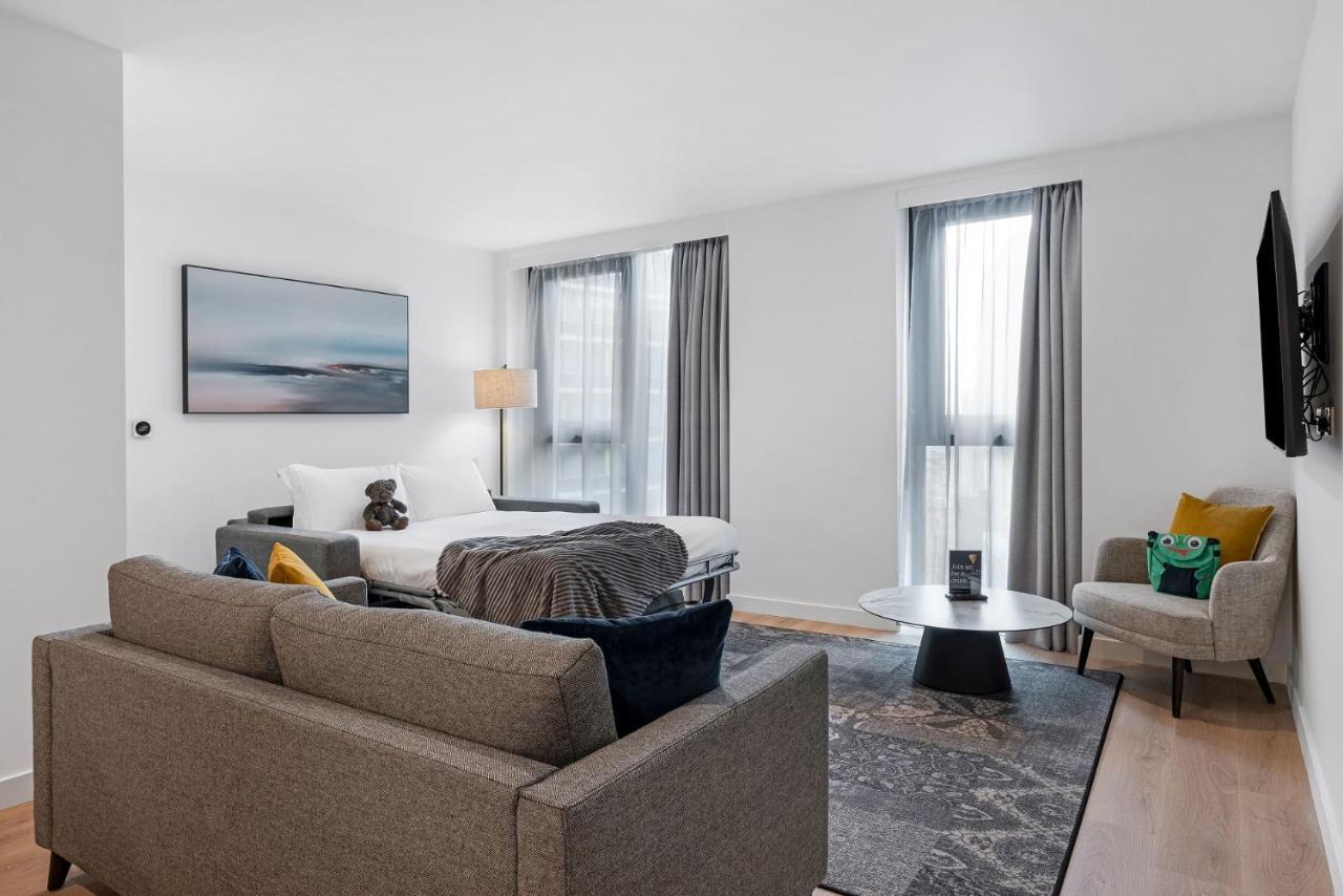 Citysuites 2 Aparthotel Селфорд Екстер'єр фото The photo shows a modern living space that incorporates a cozy and inviting atmosphere. It features a light-colored couch with colorful cushions, positioned in front of a coffee table. There's a comfortable armchair nearby, and a throw blanket is dra