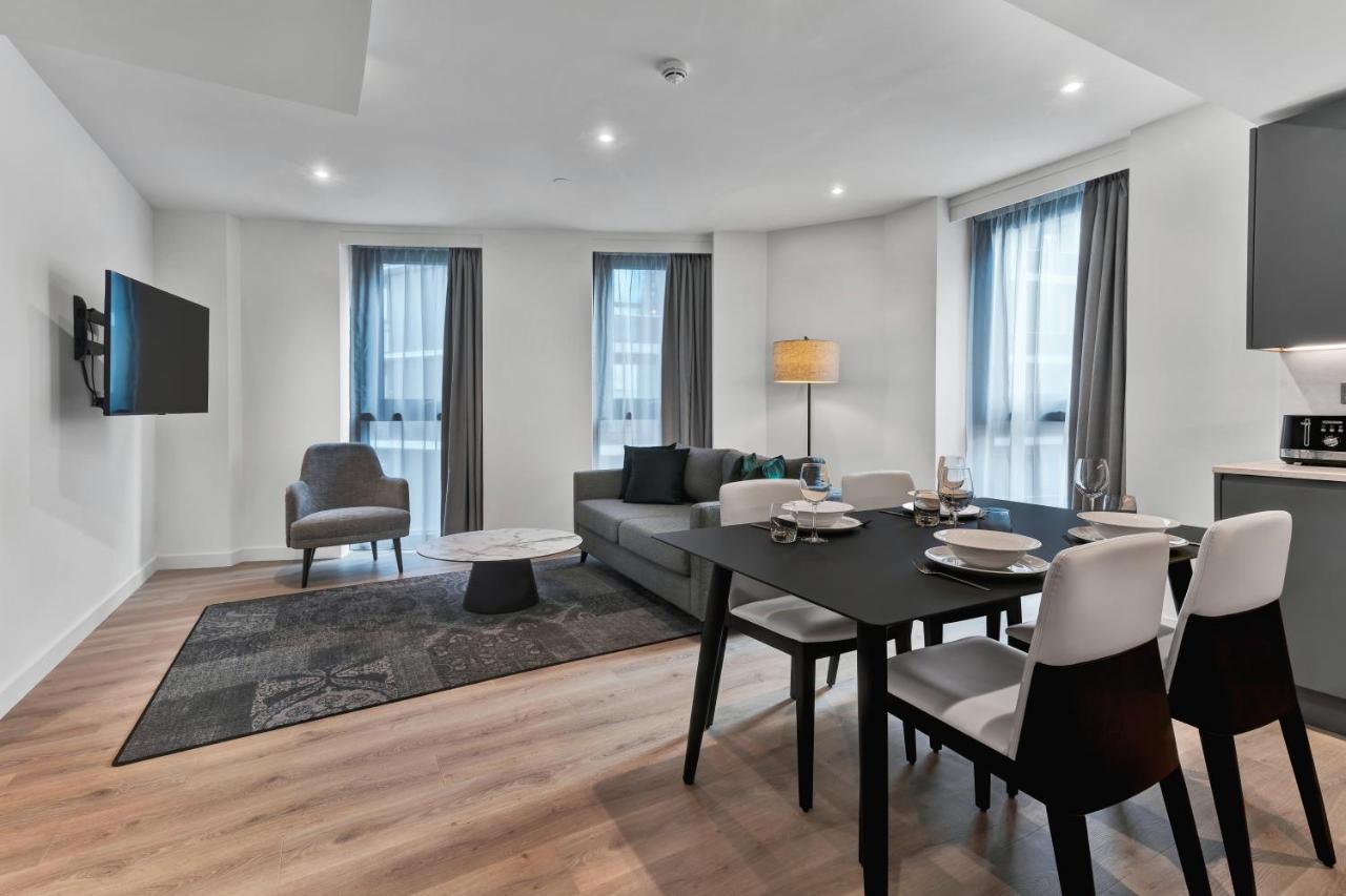 Citysuites 2 Aparthotel Манчестер Екстер'єр фото The photo shows a modern living space that includes a living area and dining area. 

- **Living Area**: There's a gray sofa with a coffee table in front of it, along with a single armchair. A large flat-screen TV is mounted on the wall. The space is 