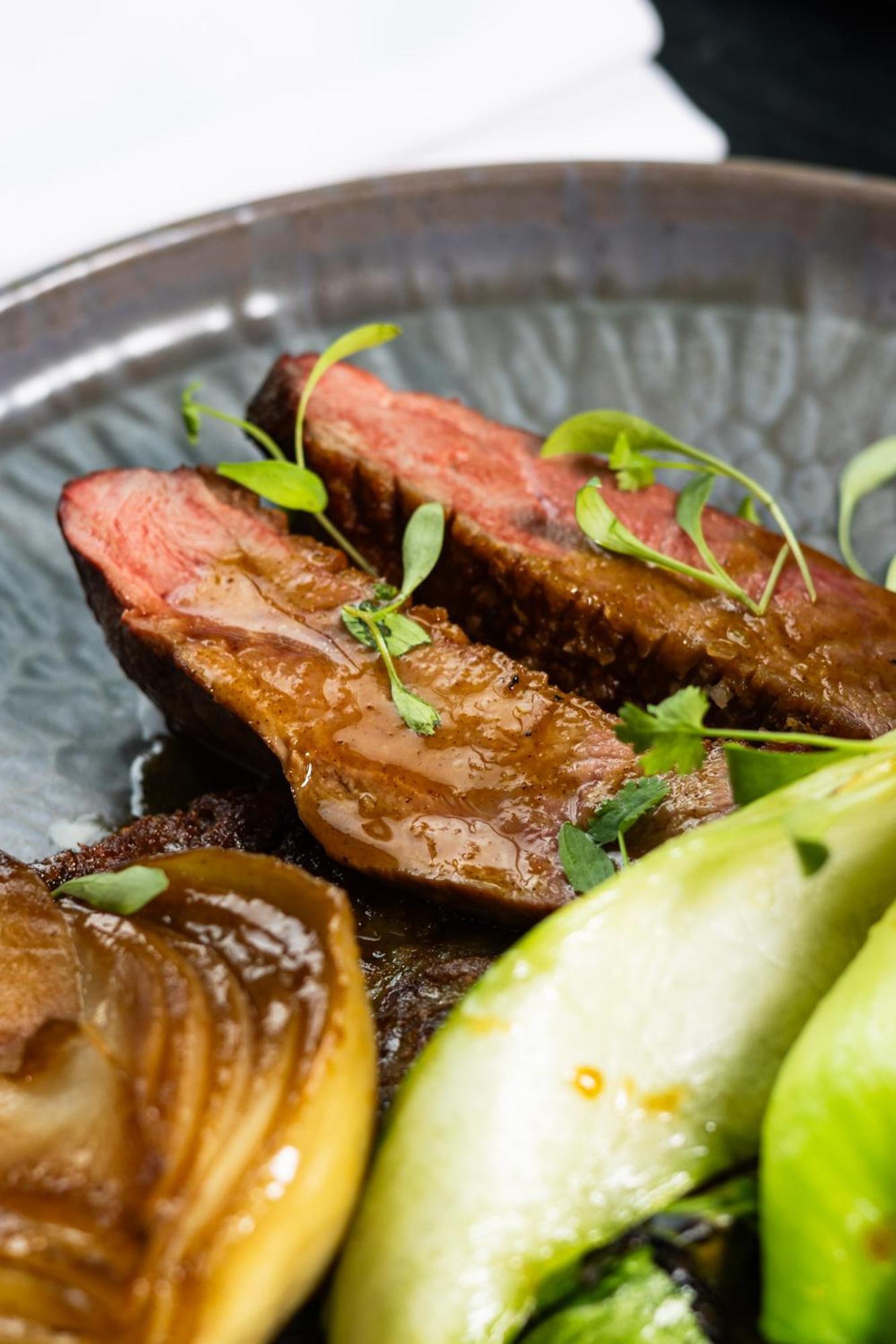 Citysuites 2 Aparthotel Манчестер Екстер'єр фото The photo features slices of meat, likely beef, presented on a decorative plate. The meat appears to have a rich brown sauce drizzled over it and is garnished with fresh herbs, adding a pop of green. There are also some slices of a light-colored vege